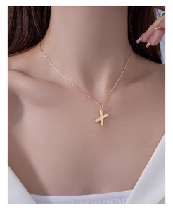 Detail of S925 silver gold necklace featuring a sparkling letter X pendant on a thin chain
