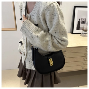 Dettaglio della borsa hobo nera minimalista con fibbia dorata sulla spalla del modello