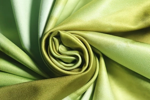 Vue macro du tissu en soie dégradé vert montrant la texture douce et le tissage sergé