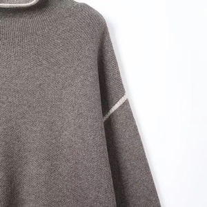 Detail of dark grey knit turtleneck featuring white stripe accents and drop shoulder design