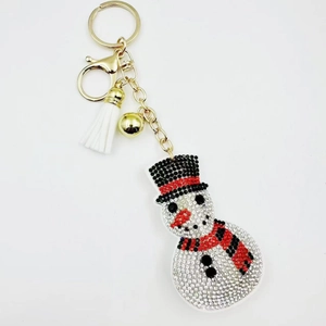 Macro detail of rhinestone snowman keychain with gold clip and white tassel charm