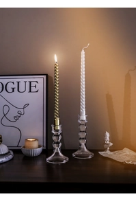 Dettaglio di eleganti portacandele in vetro geometrico con candele a spirale oro e bianco