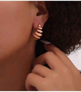 Detail of pink striped spiral geometric drop earrings on model in golden finish