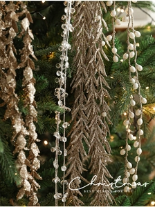 Close-up of sparkling gold glitter leaves and crystal bead garlands on a Christmas tree