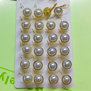 Detail view of twelve pairs of stainless steel pearl earrings on a display card
