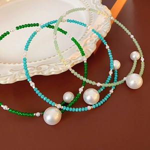 Detailed macro view of neo-Chinese pearl choker necklaces with colorful beads on a ceramic plate