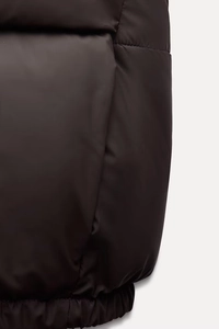 Close-up of high-density fabric texture and elastic hem on the dark brown padded vest