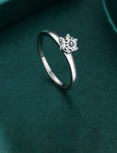 Macro detail of a classic six-prong solitaire ring on elegant dark green velvet background