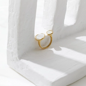 Macro detail of a gold adjustable ring featuring dual white oval shell-like inlays