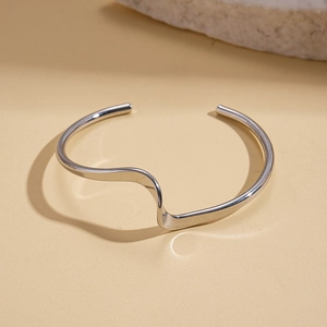 Detail view of wavy silver cuffs with a high-polished metallic mirror finish