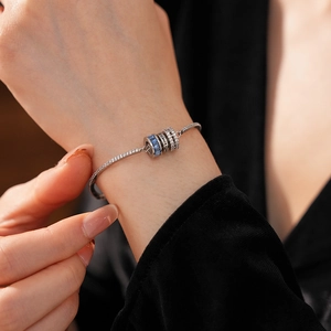 Close-up of adjustable silver bracelet with blue zircon and engraved heart charm