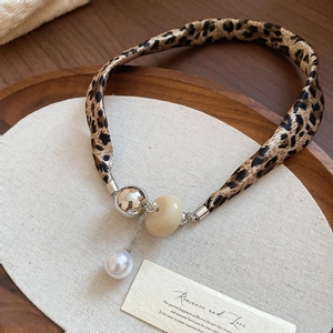 Détail du collier léopard avec perles argentées et nacre sur un plateau en bois
