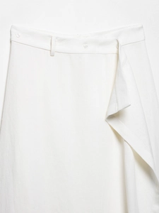 Detailed view of white high-waisted trousers featuring button closure and pleat texture
