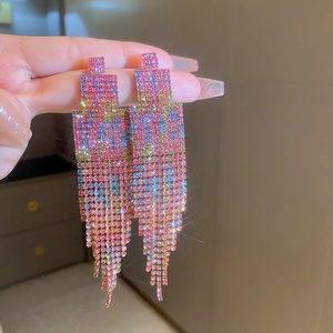 Détail de boucles d'oreilles à pompons en strass dégradés colorés avec un design frangé luxueux