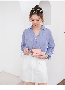 Mini portafoglio quadrato rosa minimalista con nappa decorativa tenuto da una modella