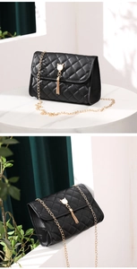 Detail of black quilted shoulder bag with gold chain and cat ear tassel pendant