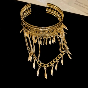 Détail d'un brassard doré avec pendentifs plumes métalliques et franges de chaîne