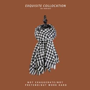 Detailed view of soft black and white houndstooth scarf with classic tassel edges