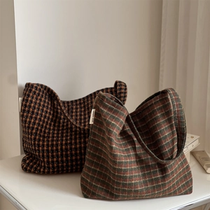Close-up of vintage plaid wool shoulder bags showing woven texture and brand labels