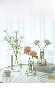 Close-up of geometric gold metal frame vases with glass tubes and artificial flowers