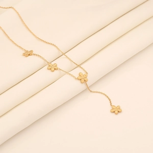 Close-up of golden flower tassel necklace on soft beige pleated fabric background