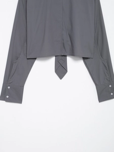 Detail of dark gray poplin shirt featuring buttoned cuffs and asymmetrical curved hemline