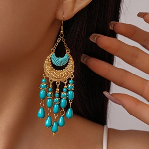 Detail of bohemian crescent earrings with turquoise beads and ethnic floral engraving
