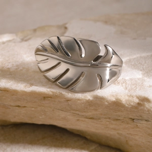 Detailed view of silver monstera leaf ring on a natural stone background