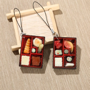 Détail des pendentifs miniatures de bento japonais sur un support en bois