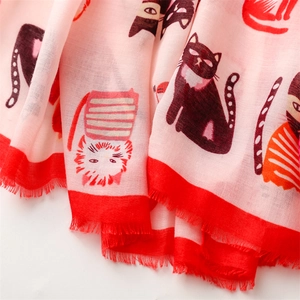 Close-up of pink silk scarf with red edges and cute cat patterns featuring fringe tassels