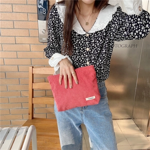 Street style view of a rose red corduroy pouch showing its size and soft texture