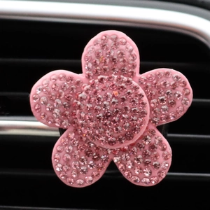 Pink rhinestone flower car vent clip shown installed on a vehicle's black air outlet