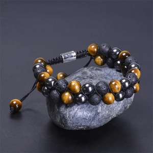 Dettaglio del bracciale doppio in occhio di tigre e pietra lavica su roccia