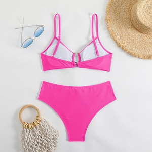 Flat lay of bright pink high waisted bikini set with sunglasses and summer accessories