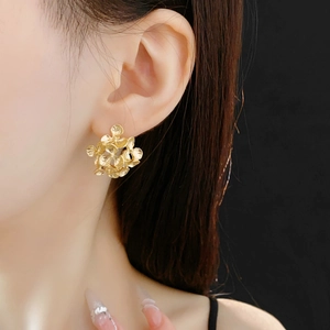 Close-up of golden cluster flower earrings with intricate 3D spherical metal design