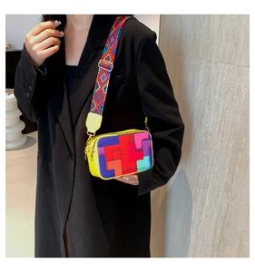 Detail view of colorful geometric patchwork shoulder bag with wide strap on model