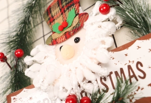 Detail eines Weihnachtskranzes mit Weihnachtsmann-Puppe, Tannennadeln und Merry Christmas