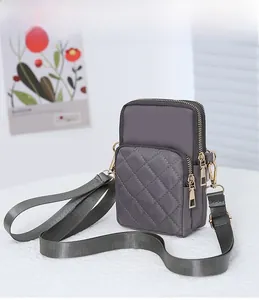 Detailed view of grey nylon quilted phone bag with gold metal zippers and strap