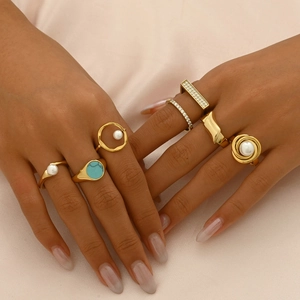 Detailed view of 7-piece gold stainless steel ring set with pearls and turquoise