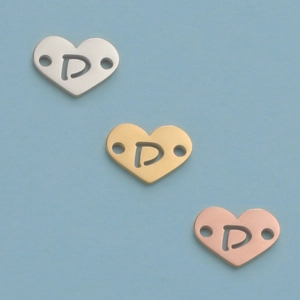 Macro detail of 12mm mirror heart charms with cut-out letter P in silver, gold, and rose gold