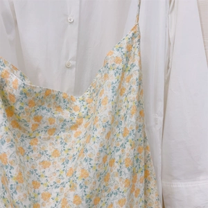 Detailed view of floral summer dress with delicate yellow and orange patterns on thin straps
