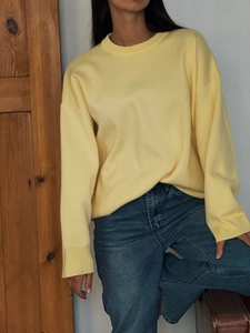 Detailed knit texture of bright yellow crewneck sweater on model with denim jeans