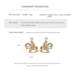 Detail view of 14k gold plated rocking horse earrings with shell and cubic zirconia