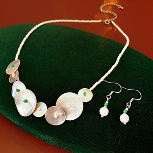 Detailed shot of beaded necklace and shell pendants on green velvet display
