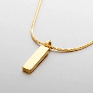 Gros plan d'un pendentif rectangulaire doré minimaliste sur une chaîne serpent fine