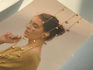 Detailed view of three gold titanium necklaces with geometric charms and zircon stones