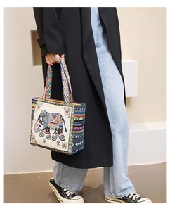 Detailed embroidery of elephant pattern on ethnic style canvas tote bag with woven handles