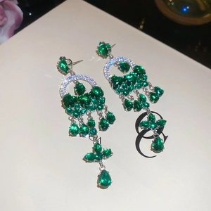 Detailed macro view of silver drop earrings with green faceted gems on a jewelry box