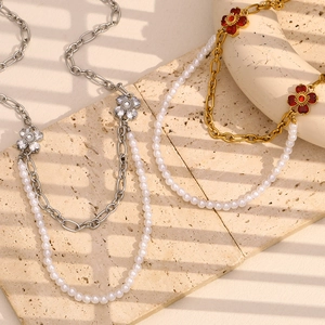 Artistic close-up of 18K gold and silver plated flower pearl necklaces on textured stone