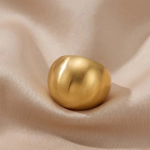 Detailed macro view of wide gold plated ring with brushed texture on beige silk fabric